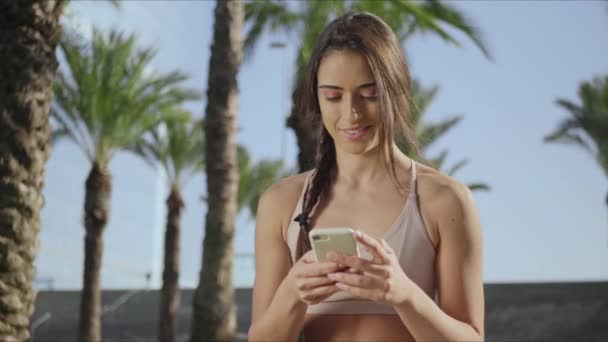 Yoga tränare med smartphone i parken efter träning.Lady skriva på telefon i parken — Stockvideo