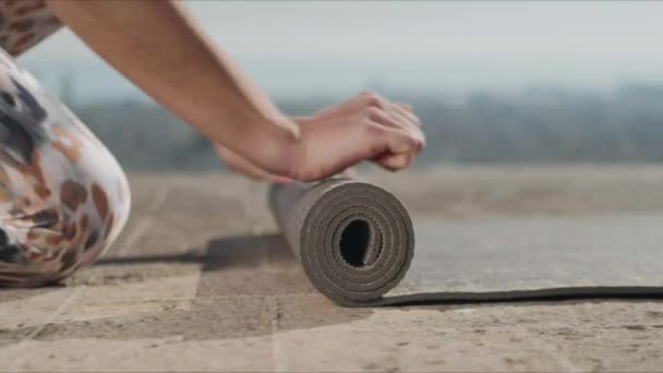 Kvinnliga händer rullar upp yogamattan efter träning.Flicka fällbar träningsmatta utomhus — Stockvideo