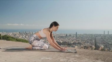 Açık havada yoga yaparken akıllı telefondan video dersi alan sporcu bir kadın..