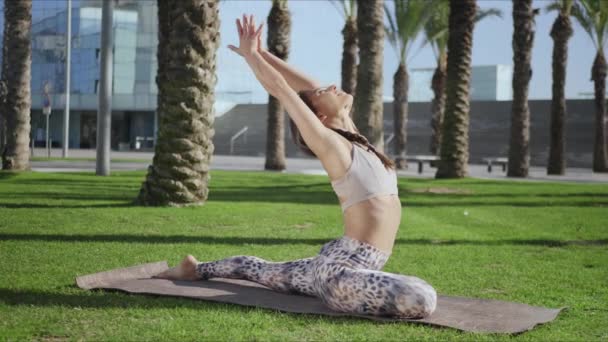 Chica atlética estirándose en el parque. Mujer haciendo ejercicios de yoga sobre hierba verde — Vídeo de stock