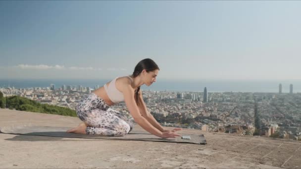 Mujer deportiva mirando video lección en el teléfono inteligente durante el entrenamiento de yoga al aire libre . — Vídeos de Stock