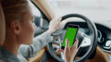 Arabada yeşil ekran telefon kullanan bir kadının portresi. Akıllı telefon tutan kadın