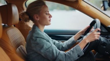 İş kadınının arabada dans edişinin yan görüntüsü. Ön koltukta oturan neşeli kadın.