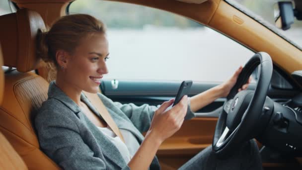 Вид сбоку на женщину, держащую телефон в машине. Бизнесмен, сидящая с телефоном у машины — стоковое видео
