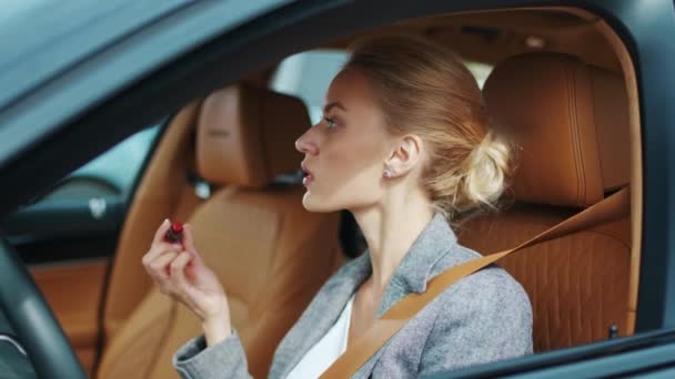 Closeup woman applying red lipstick in vehicle. Sexy woman sitting in luxury car — Stock Video