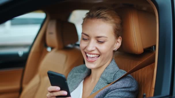 Деловая женщина крупным планом пользуется телефоном в машине. Женщина-водитель улыбается на переднем сиденье — стоковое видео