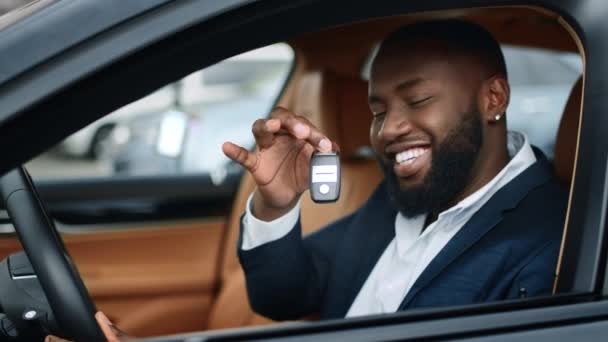 Yakın plan iş adamı yeni arabasında anahtar sallıyor. Afrikalı adam araçta gülümsüyor — Stok video