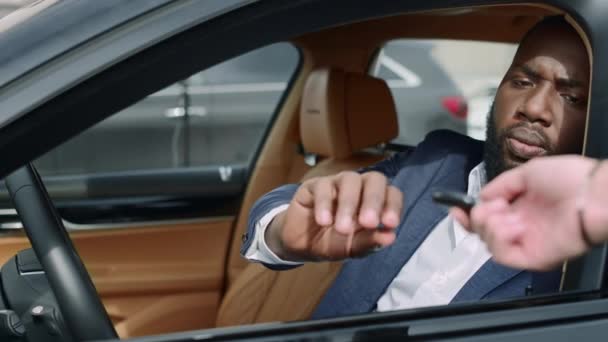 Primer plano hombre africano sentado frente al coche. Empresario tomando la llave en el vehículo — Vídeos de Stock
