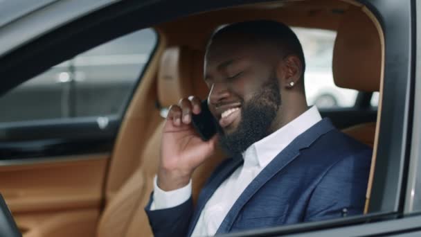Een close-up Afrikaan die de telefoon in de auto gebruikt. Afrikaanse man aan het praten mobiel op voertuig — Stockvideo