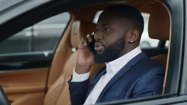 Närbild afro man pratar telefon vid bilen. Mannen sitter vid framsätet i lyxbilen — Stockvideo