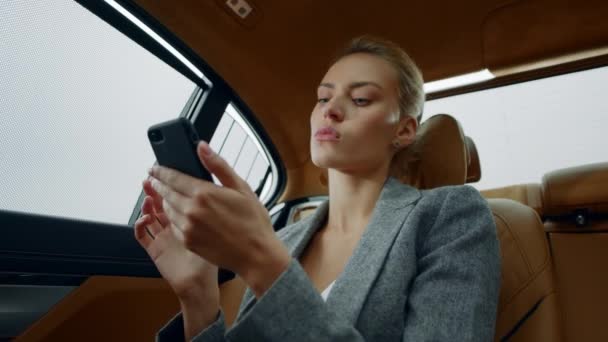 肖像画の女性の携帯電話の後部座席に座っている。車のスマートフォンを使う女性 — ストック動画