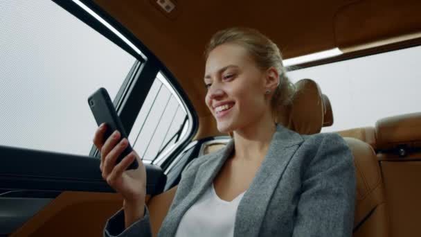 Porträt einer fröhlichen Frau, die am Auto mit dem Handy im Internet surft. — Stockvideo
