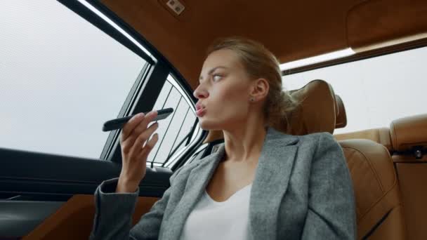 Close-up ernstige zakenvrouw opnemen spraakbericht op mobiele telefoon in de auto. — Stockvideo