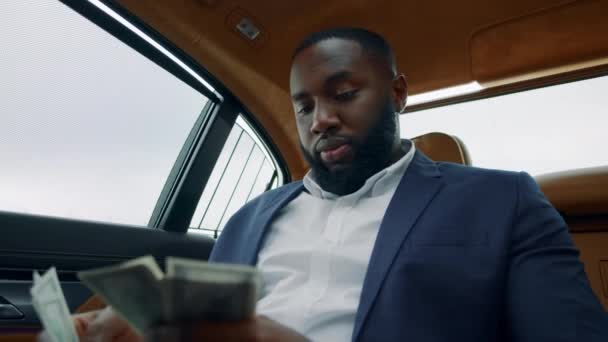 Porträt eines Geschäftsmannes, der am Auto Geld zählt. Afrikaner riecht Geld am Auto — Stockvideo