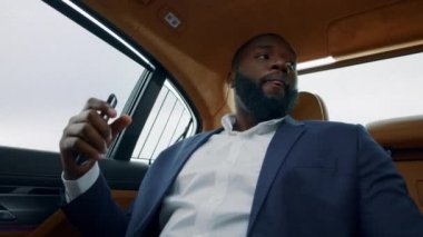 Kostümlü Afrikalı adam arabada dans ediyor. Aracın içinde müzik dinleyen Afro işadamı