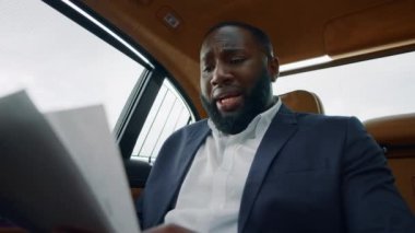 Arabadaki belgeleri okuyan Afrikalı bir adam. Elinde kağıtlar tutan kafası karışık bir adam.