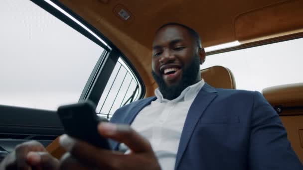 Glücklicher Geschäftsmann feiert Sieg am Auto. Afro-Typ macht Ja-Geste — Stockvideo