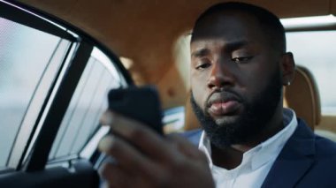 Arka koltukta cep telefonu yazan Afrikalı iş adamının portresi..