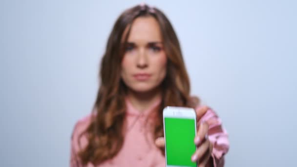 Empresaria mostrando smartphone con pantalla verde en estudio — Vídeos de Stock