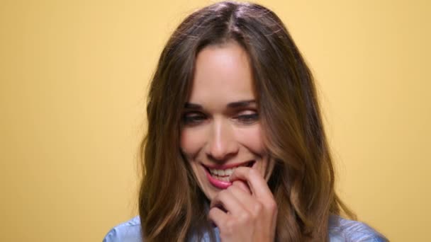 Mujer alegre riendo sobre fondo amarillo. Chica alegre coqueteando en la cámara — Vídeo de stock