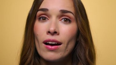 Sarı arka planda sürpriz bir kadın. Kameraya gülen kadın