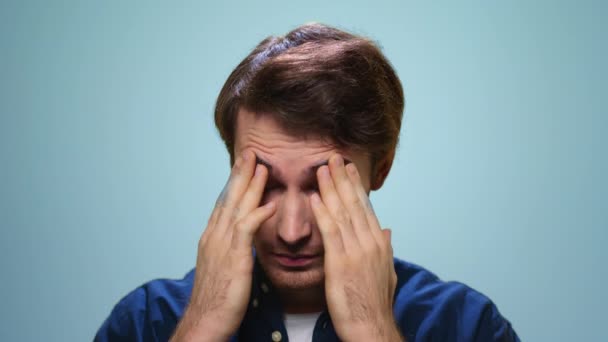 Porträtt av trött man med huvudvärk. Stressad man ansikte på blå bakgrund — Stockvideo