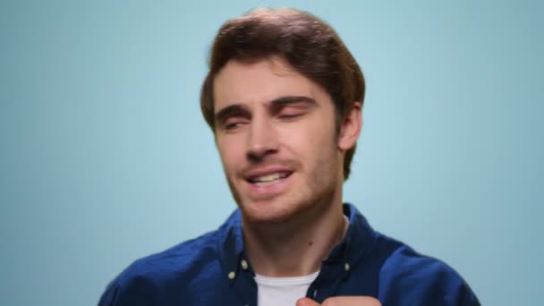 Hombre sonriente bailando en el estudio. Tipo positivo cantando canción sobre fondo azul — Vídeo de stock