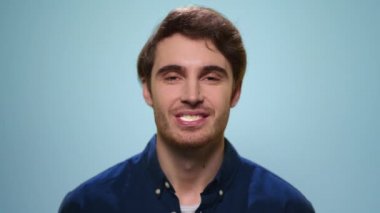 Gülümseyen adam stüdyoda sakız çiğniyor. Kamerada baloncuk çıkaran yakışıklı adam.