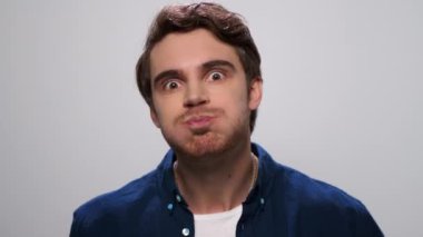 Yakışıklı adam komik suratlar yapıyor. Stüdyoda surat asan erkek model.