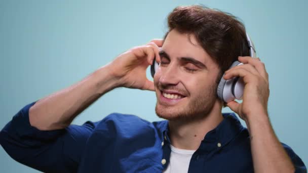 Usmívající se muž si nasadil sluchátka ve studiu. Chlápek, co poslouchá hudbu ve sluchátkách — Stock video
