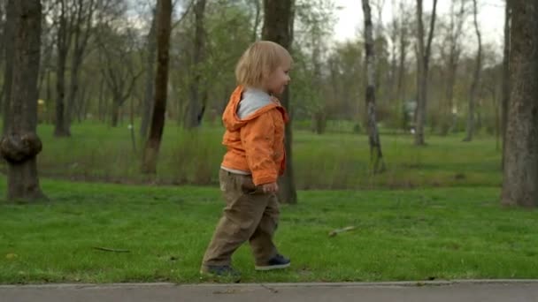 Bébé mignon marchant dans le parc au ralenti. Petit garçon courant à l'extérieur