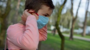 Bahçede tıbbi maske takan genç bir adam. Dışarıda maske takan genç bir çocuk.