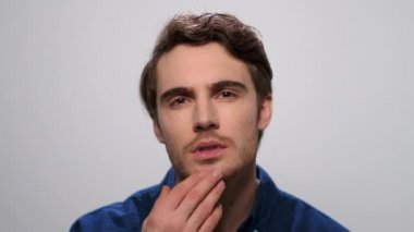 Stüdyoda sakalı kontrol eden adam. Sakallı adam elleriyle yüzüne dokunuyor.