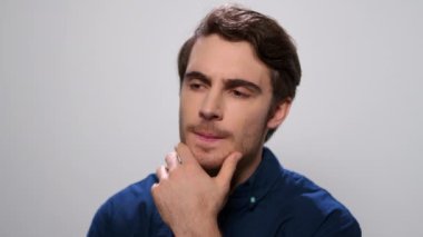 Stüdyoda ciddi düşünen bir adam. Erkek öğrenci elleriyle yüzüne dokunuyor.