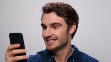 Beyaz arka planda cep telefonu kullanan bir adam. İnternette cep telefonuyla gezinen adam.