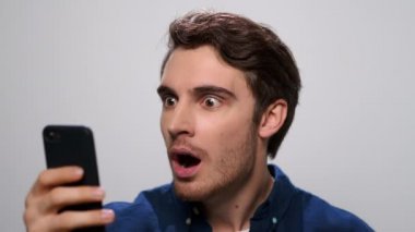 Stüdyoda akıllı telefondan haber okuyan şok olmuş bir adam. Cep telefonu kullanan adam.