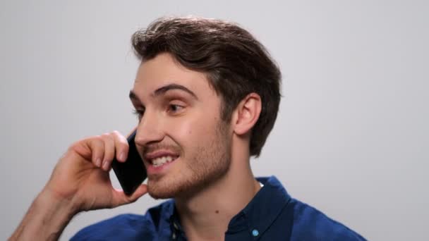 Hombre positivo hablando en smartphone sobre fondo claro. Un tipo llamando al celular. — Vídeos de Stock