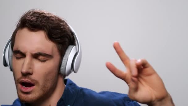 Homem a ouvir música nos auscultadores. Guy dançando em fones de ouvido no fundo de luz — Vídeo de Stock