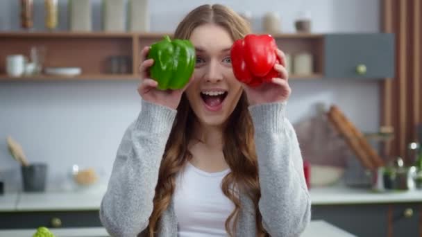 Portrait de jeune femme changeant les émotions avec des poivrons colorés à la maison cuisine . — Video