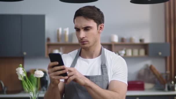 Muž kuchař hledá recept na mobilní telefon. Šéfkuchař hledá telefonní obrazovku v kuchyni. — Stock video