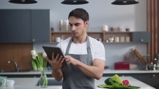 Šéfkuchař čte recept na tabletu v kuchyni. Man Chef Browsing Internet. — Stock video
