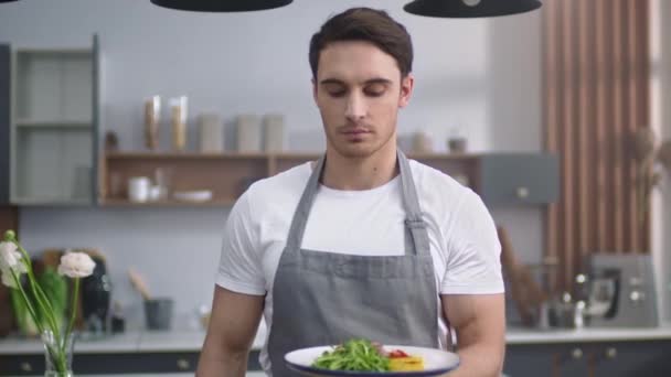 Чоловік готує салат з запахом на домашній кухні. Веселий шеф-кухар, що представляє здорову їжу — стокове відео