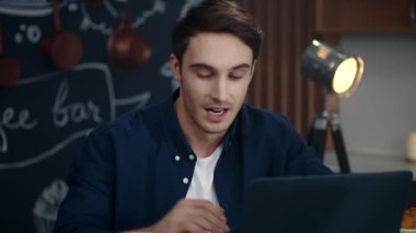 Evdeki bilgisayarında video kaydı olan mutlu bir adam. İş adamı kahve içiyor.