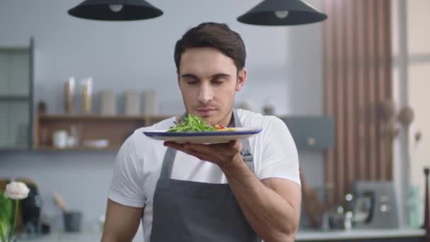 Portrait de chef souriant homme tenant assiette avec salade à la maison cuisine . — Video