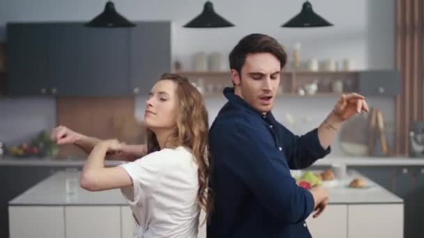 Gelukkig man en vrouw dansen rug naar rug thuis keuken in slow motion. — Stockvideo