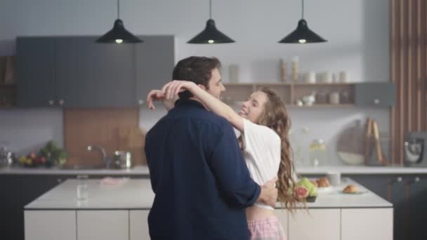 Una pareja de enamorados bailando lentamente en la cocina. Dos personas elegantes disfrutando del tiempo juntos — Vídeos de Stock