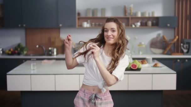 Mujer alegre bailando en la cocina casera. Sexy dama chasquido dedos en el interior — Vídeo de stock