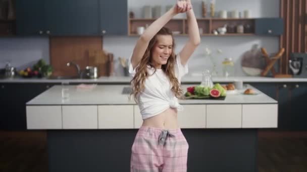 Žena tančí s mobilem v ruce doma. Roztomilá dívka s úsměvem na kameru — Stock video