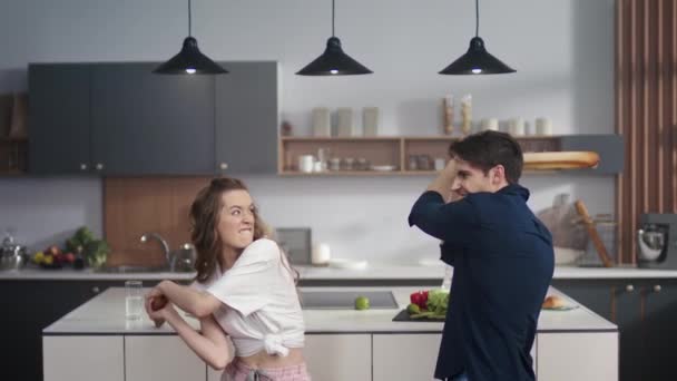男人和女人在厨房里用滚动式别针打架.夫妻在家里玩的开心 — 图库视频影像