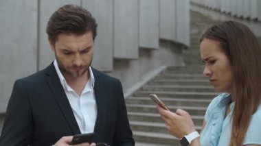 Sokakta dikilen kadın ve erkek. Akıllı telefon kullanan iş çifti